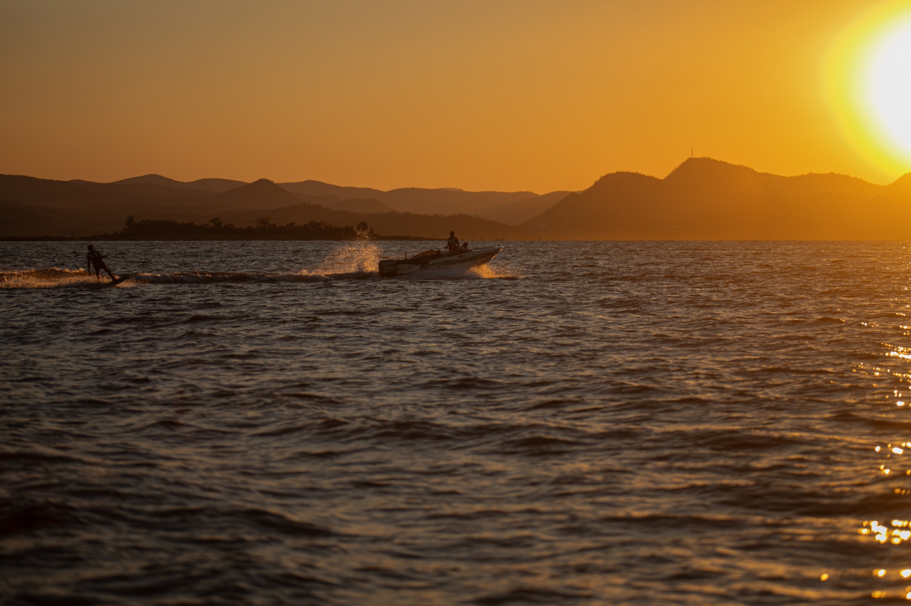 Golden-hour lake with wakeboarding in the distance