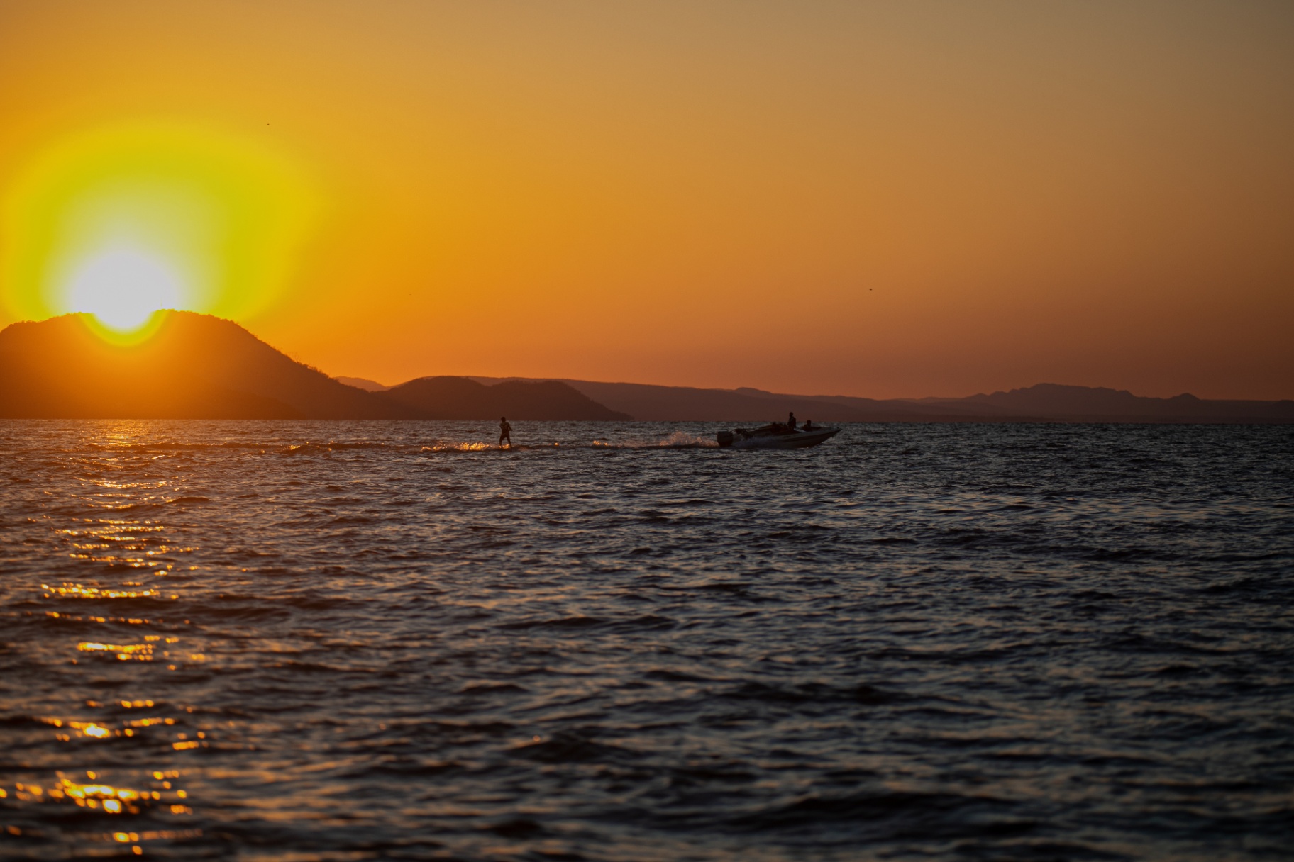 Golden-hour lake with wakeboarding in the distance
